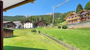 Un pueblo montañoso rural con casas de madera tradicionales, cielo despejado y vistas de las colinas circundantes.
