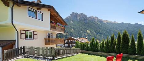 A two-story building with balconies, a wooden fence, and a mountain view.