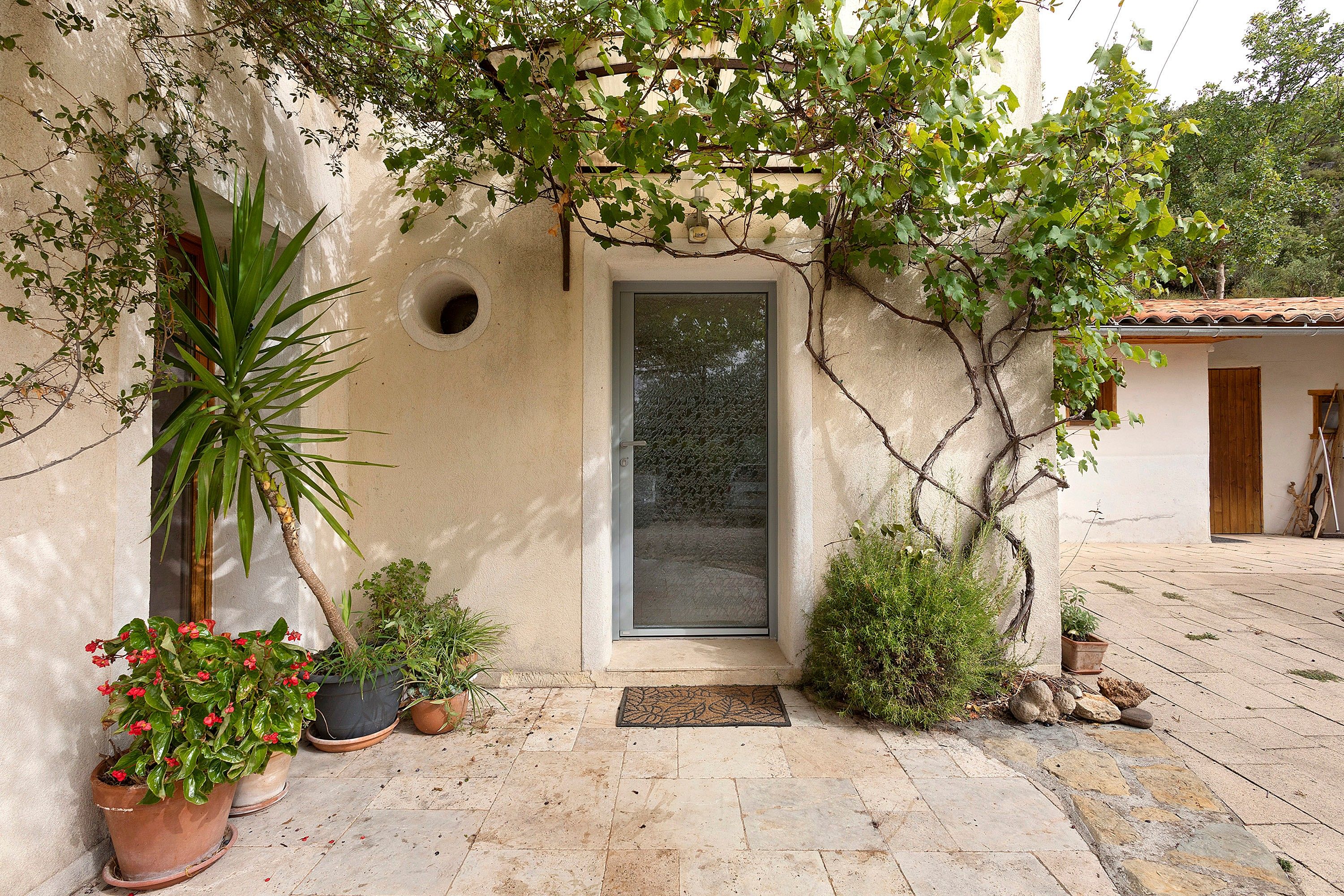 A courtyard with a door, potted plants, and a tiled floor.