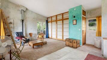 A spacious room with a large sliding door, a wooden bench, a fan, and a suitcase.