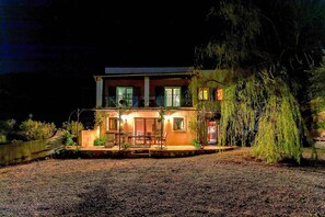 Une maison à deux étages avec un balcon, un porche à l’avant et une allée gravillonnée.