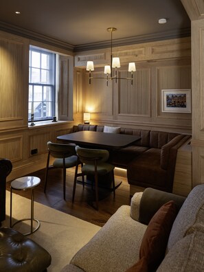Ein Essbereich mit einer holzverkleideten Wand, einer Kronleuchter, einem Tisch mit Stühlen und einem Sofa.