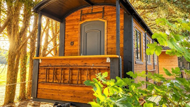 A wooden cabin with a large door, a small porch, and a window. - Cowboy Trailer - Unique Tiny House (Mignaloux-Beauvoir)