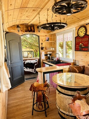 Un interior de madera con una zona de bar, una mesa redonda y un reloj en la pared.
