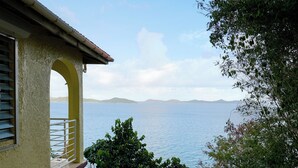 A building with a balcony overlooking a body of water and distant landforms. - Haversville Canary Studio with stunning ocean views on Tortola, Virgin Islands (Tortola)