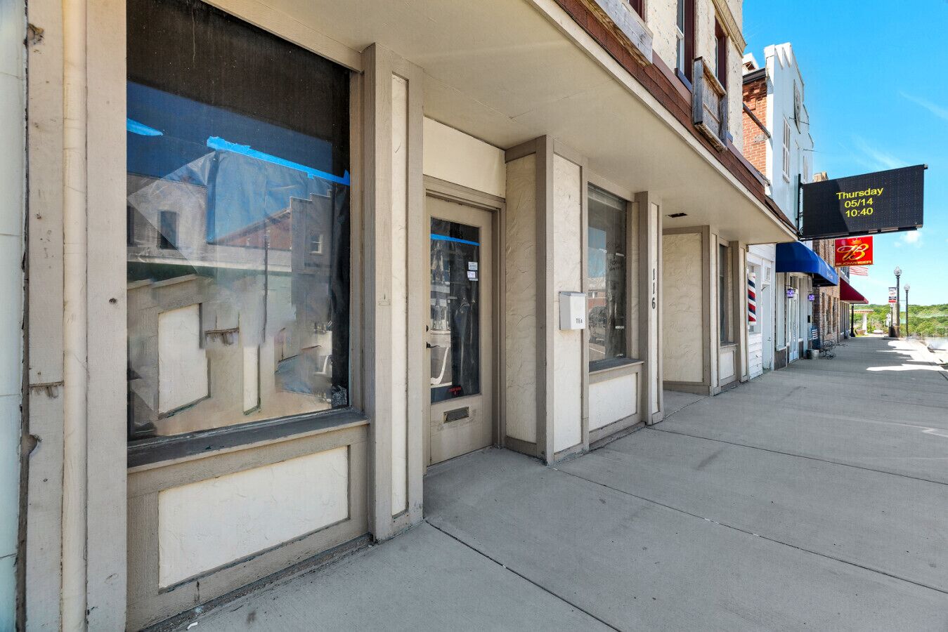 A row of closed storefronts with large windows and a sidewalk.