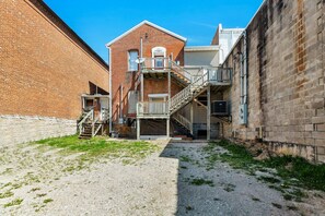 A building with a brick facade, a staircase leading to a balcony, and a gravel ground.