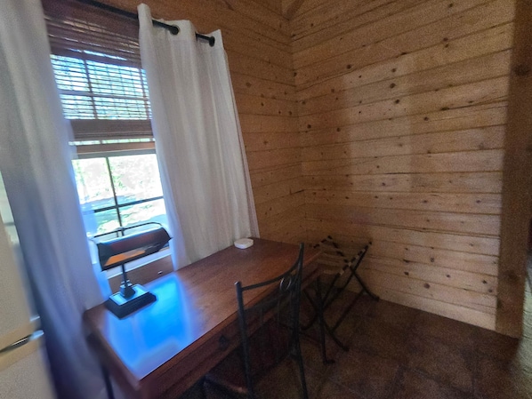 A wooden-paneled room with a table and chairs, a window with curtains, and a view outside.