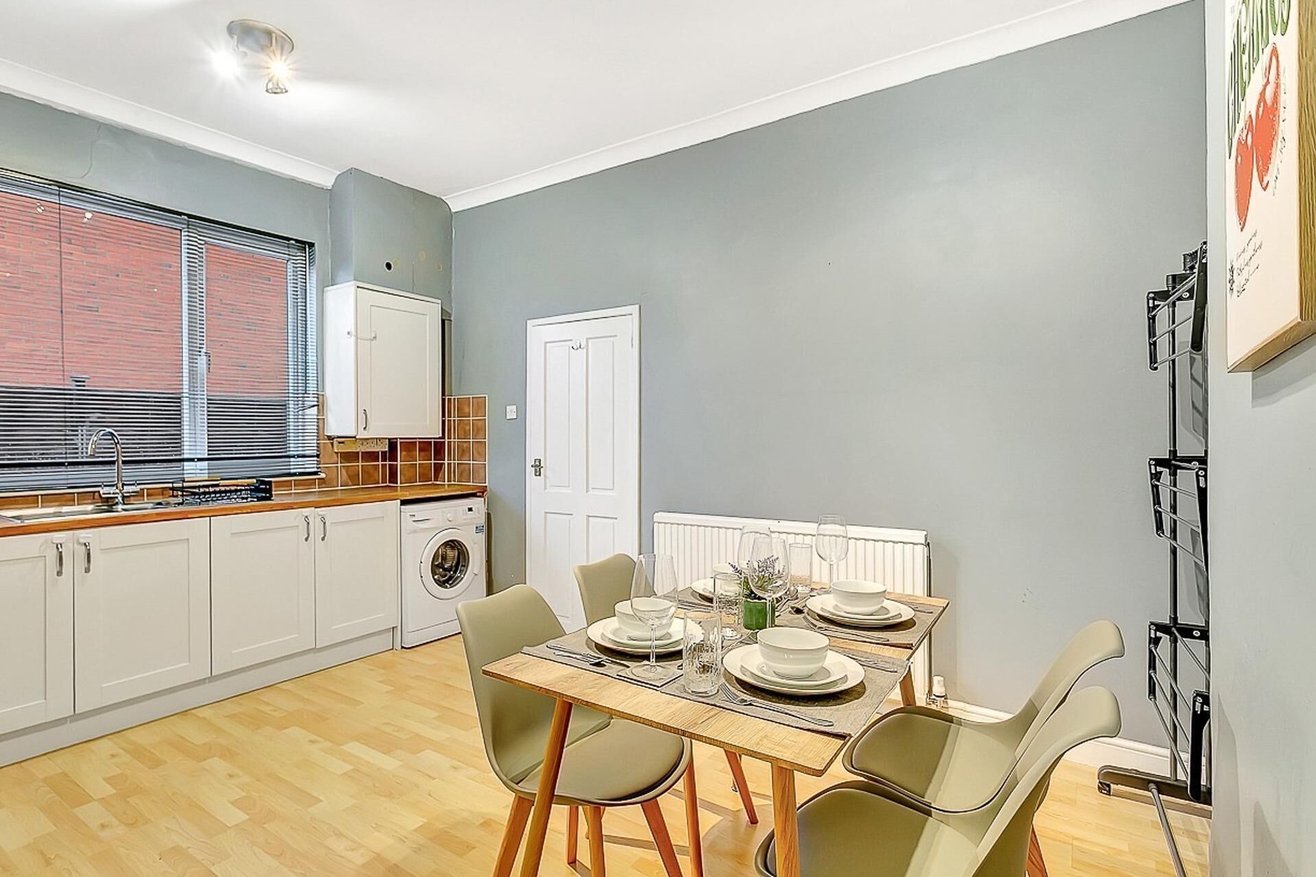 Une cuisine compacte avec un coin repas, un lave-linge et un radiateur.