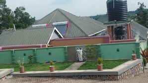 Un edificio con fachada verde, un tanque de agua y un panel solar.