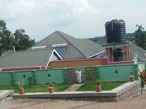 A building with a green exterior, a water tank, and a solar panel.