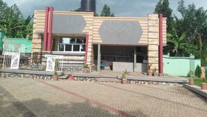 Un edificio de techo plano, con un depósito de agua en la parte superior y un área de acceso pavimentada con plantas en macetas.