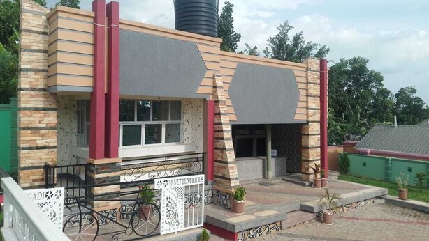 Un edificio con fachada de piedra, un tanque elevado en el techo y una entrada con portones.