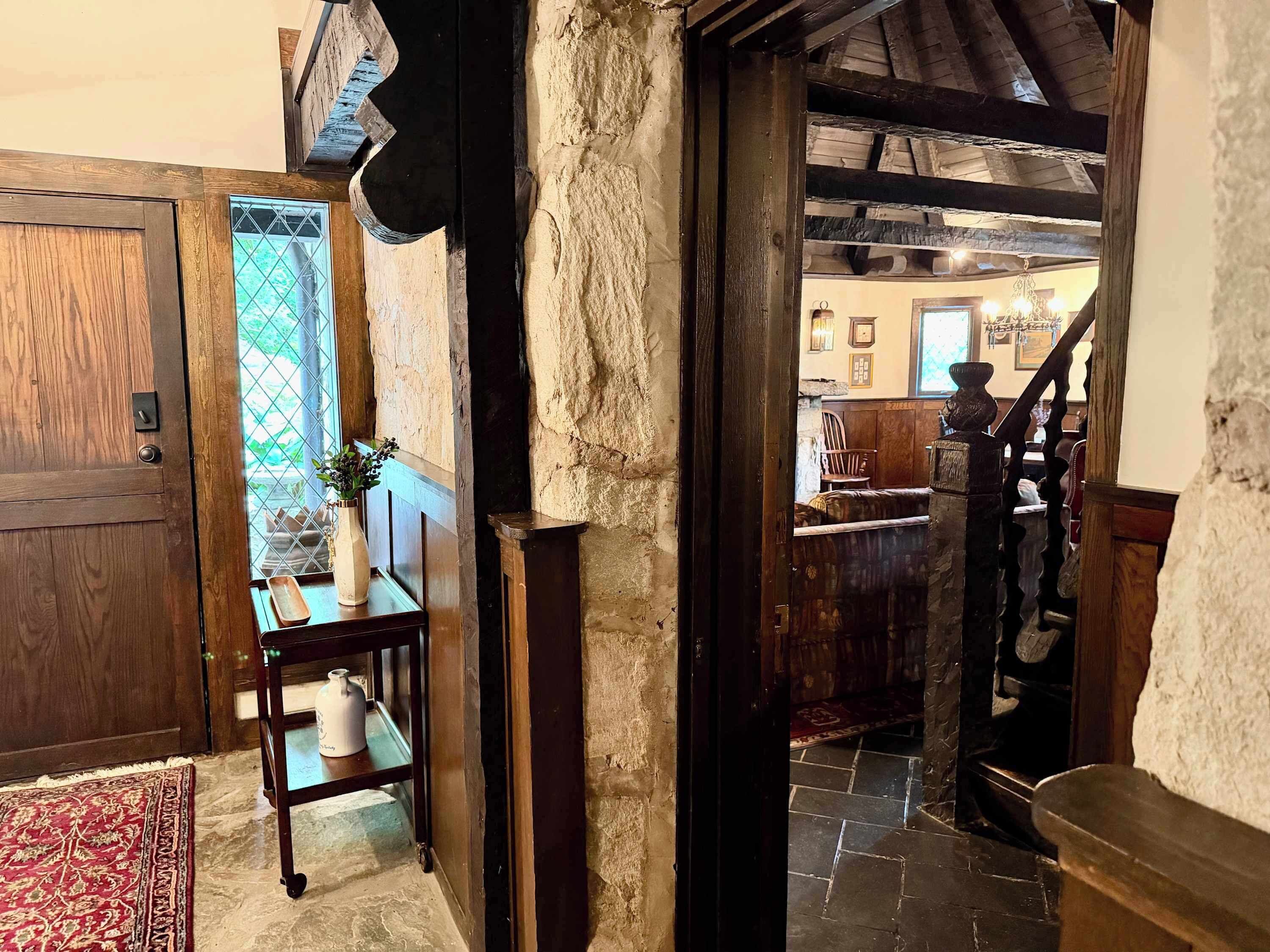 Un intérieur rustique avec une porte en bois, un mur en pierre et un escalier menant à une autre pièce.