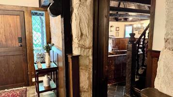 Un intérieur rustique avec une porte en bois, un mur en pierre et un escalier menant à une autre pièce.