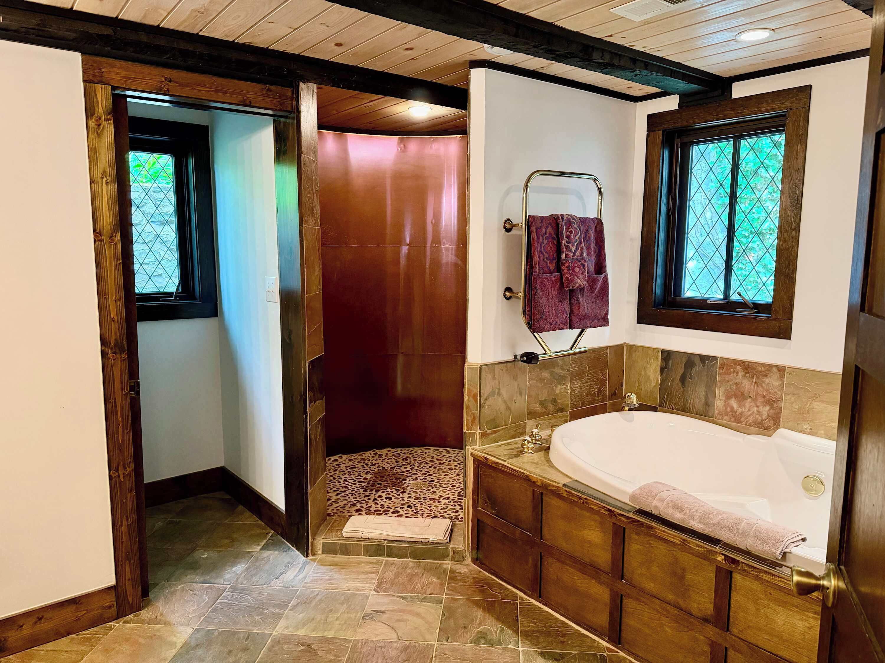 A bathroom with a bathtub, a shower area, and a window.