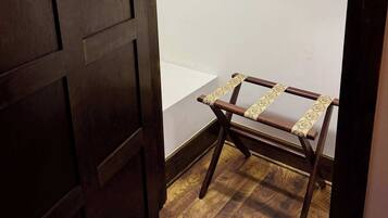 A wooden wardrobe with a mirror, a hanging clothes rack, and a small wooden table.