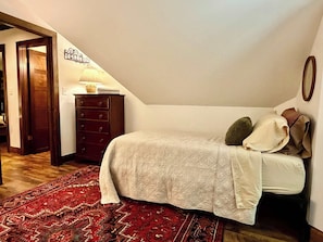 A bedroom with a bed, a dresser, a lamp, a rug, and a wall decoration. - Tynecastle Retreat - Views, Game Room & Patio (Banner Elk)