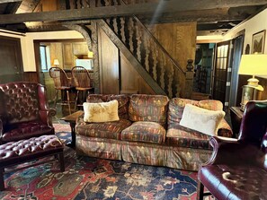 A cozy living room with a patterned sofa, leather armchairs, and a traditional rug.