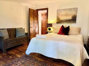 A bedroom with a bed, a wooden bench, a rug, a painting, and a door. - Tynecastle Retreat - Views, Game Room & Patio (Banner Elk)