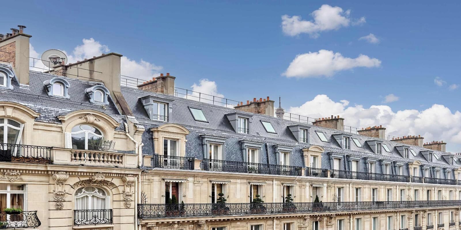 A row of classic European-style buildings with uniform architecture, featuring balconies and large windows.