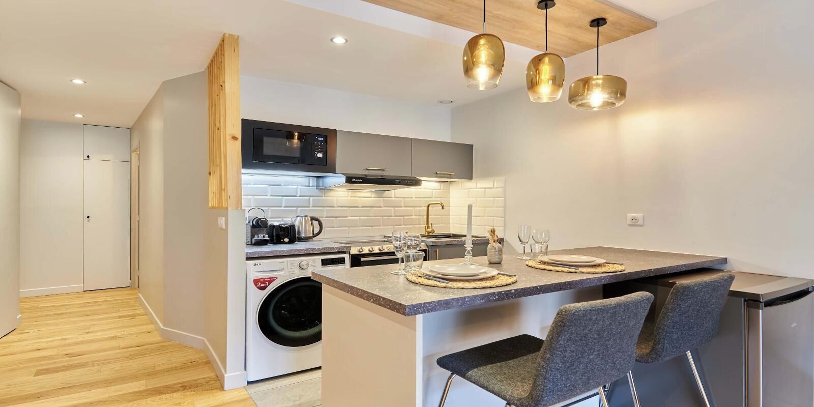 Una cocina moderna con lavadora integrada, microondas y fregadero.