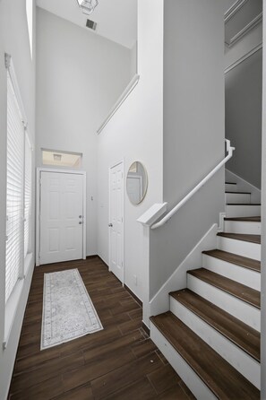 Un escalier avec des marches en bois et une rampe blanche, une porte blanche et une petite fenêtre.
