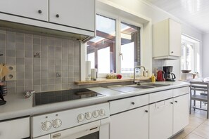 Eine Küche mit großem Fenster, einem Herd und einem Spülbecken.
