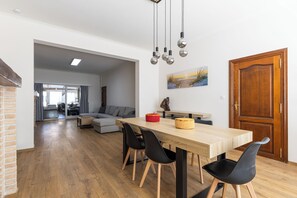 A modern dining area with a wooden table, black chairs, and hanging light fixtures.