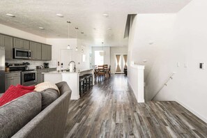 A modern kitchen with grey cabinets, a microwave, and a dining area with a wooden table and chairs.