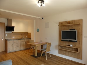 Eine moderne Küche mit Holzausbau, inklusive Einbauherd und einem flachbildfernseher an einer Holzwand.