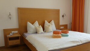 Uma cama bem arrumada com almofadas, uma mesinha de cabeceira com um telefone e uma luminária.
