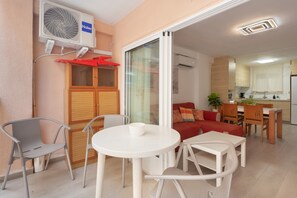 A compact living space with a dining area, kitchenette, and a sliding glass door leading to an outdoor area. - ‘Luz y Playa’ Apartment with Private Terrace, Wi-Fi, and Air Conditioning (Cullera)