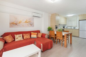 Un salon moderne avec un canapé rouge, une table basse blanche et un coin repas comprenant des chaises et une table en bois.