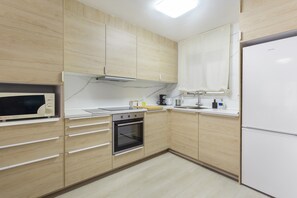 Une cuisine moderne avec des meubles en bois, un four à micro-ondes encastré, une cuisinière et un réfrigérateur.