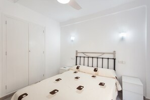 A bedroom with a bed, bedside tables, a wardrobe, and a ceiling fan. - ‘Luz y Playa’ Apartment with Private Terrace, Wi-Fi, and Air Conditioning (Cullera)