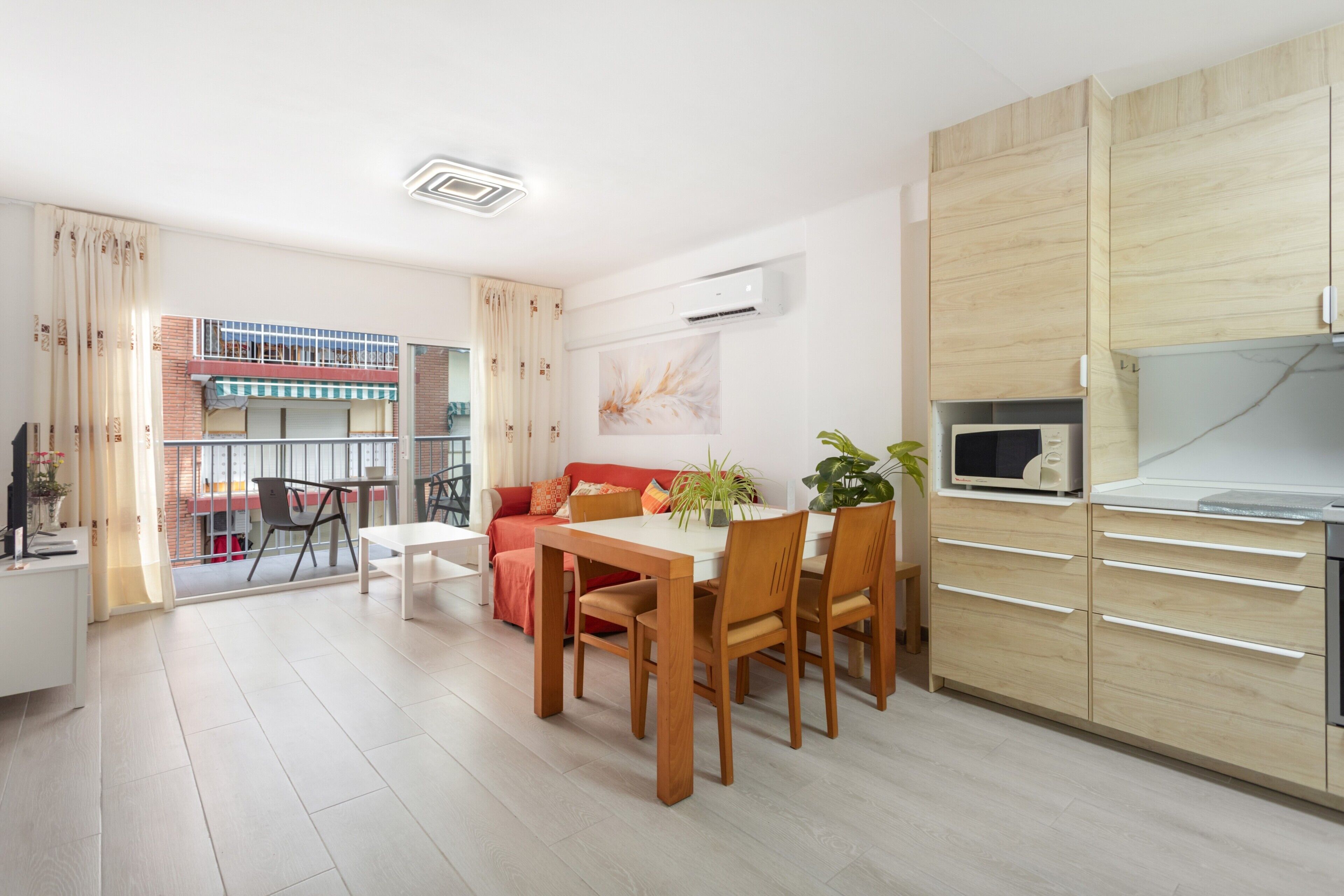 A modern kitchen with a microwave, wooden cabinets, and a dining area with a table and chairs.