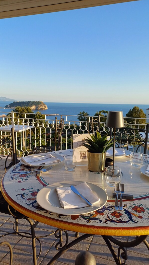 A table set for dining with a view of the sea and a distant island.