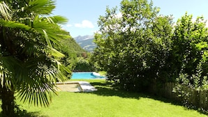 Un giardino sul retro con piscina, vegetazione lussureggiante e recinzione in legno.