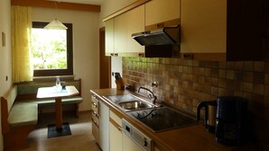Una cucina con piano cottura integrato, lavello e finestra con tende.