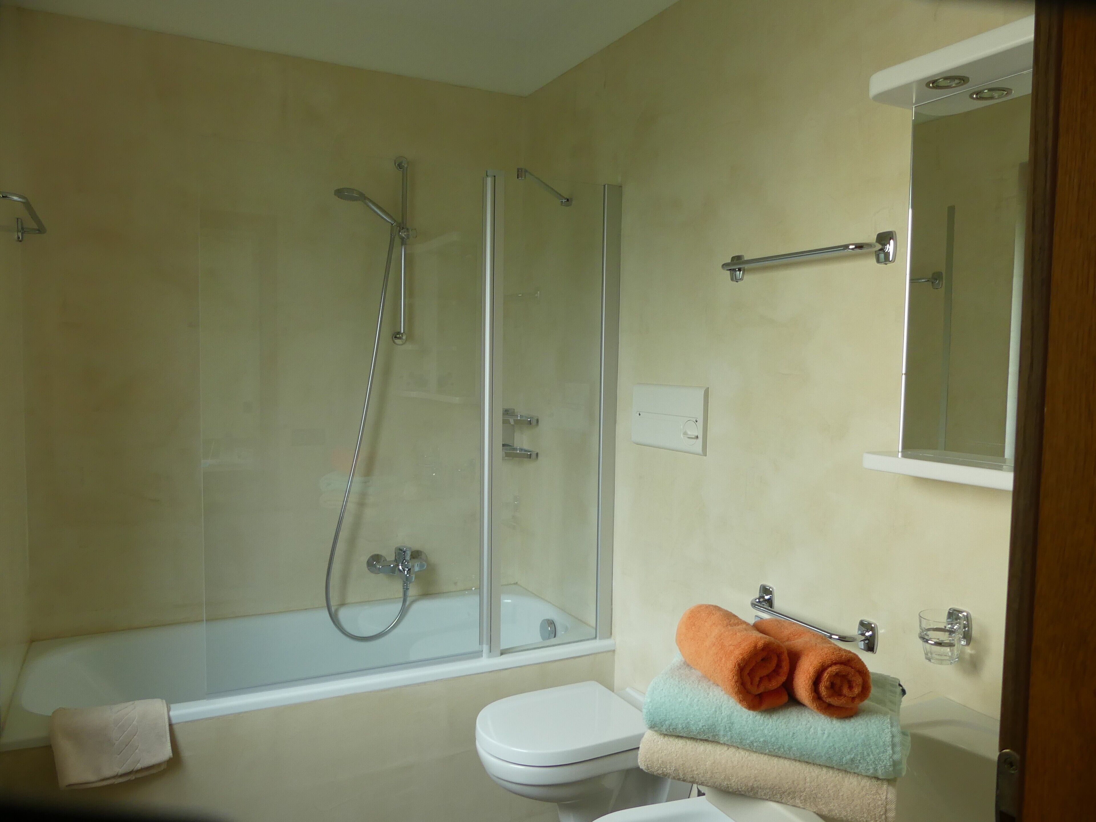 A bathroom with a glass-enclosed shower, a toilet, and a sink.