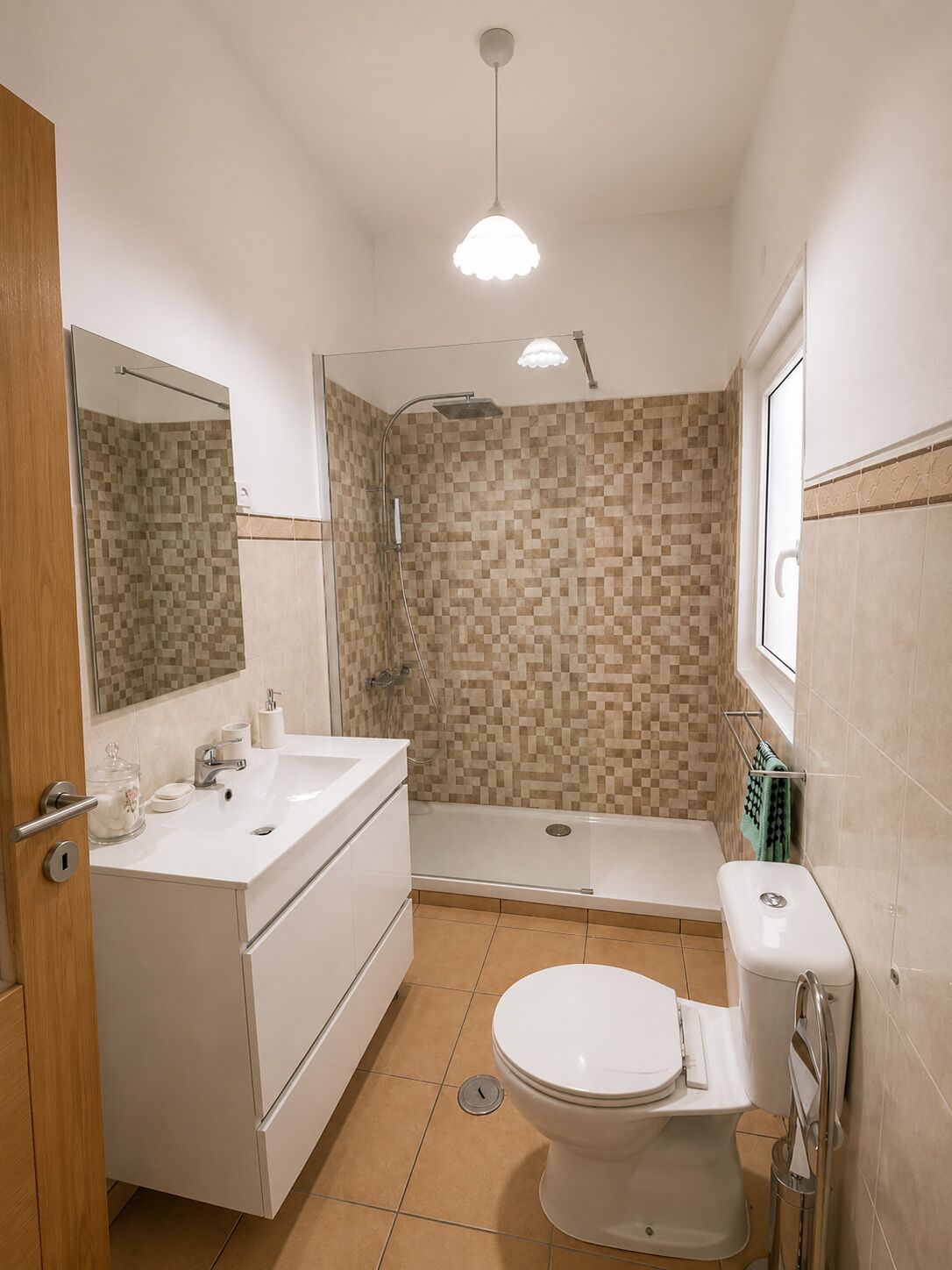 A bathroom with a shower, toilet, sink, and mirror.