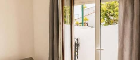 Una sala de estar moderna con un sofá, un ventanal corredero que da a un espacio exterior y una lámpara de techo.