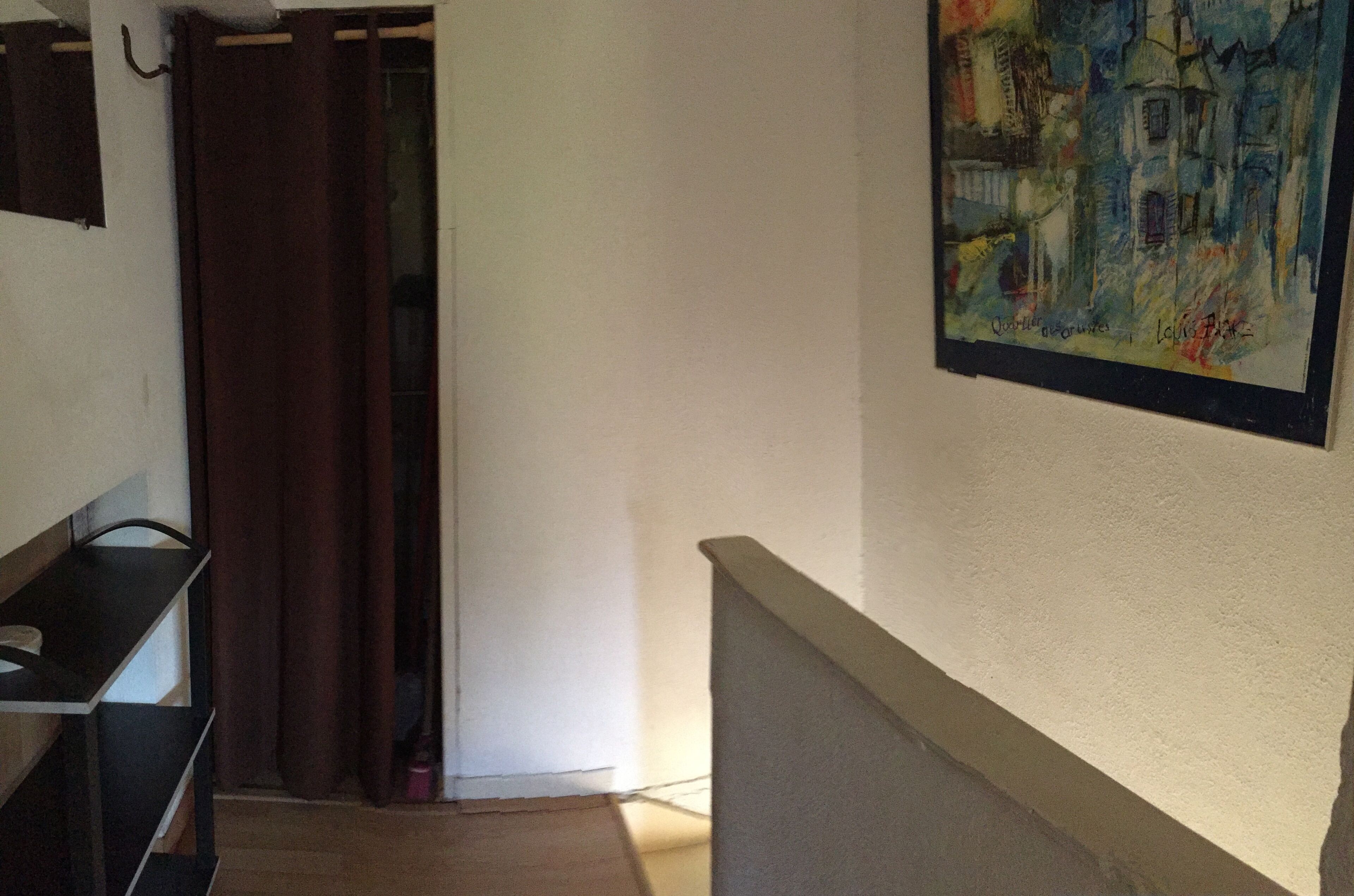 Ein Flur mit einem Gemälde, einer Treppe und einer Tür mit Vorhang.