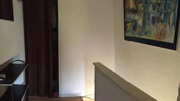 Ein Flur mit einem Gemälde, einer Treppe und einer Tür mit Vorhang.