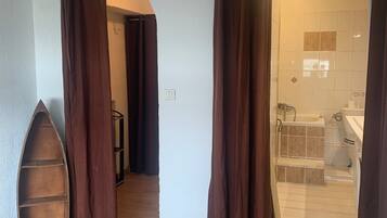 Ein Schlafzimmer mit einem Bett, einem Holzregal und einem Badezimmer mit Waschbecken und Toilette.