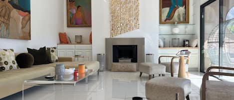 Uma sala de estar moderna com sofá, mesa de centro, lareira e obras de arte nas paredes.