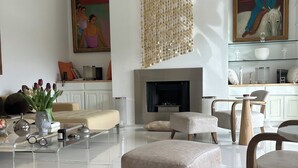 Ein modernes Wohnzimmer mit Kamin, Poufs und Deckenventilator.