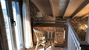 A wooden interior with a stone wall, a table, chairs, and a lamp. - Aegean Retreat for 6 Pool & Evia Views Near Athens (Chalcis)