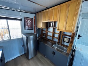 A compact kitchen with a refrigerator, wooden cabinets, a sink, and a window. - Tiny home available in Algona Pacific.  Right off of 167 close to amenities. (Pacific)
